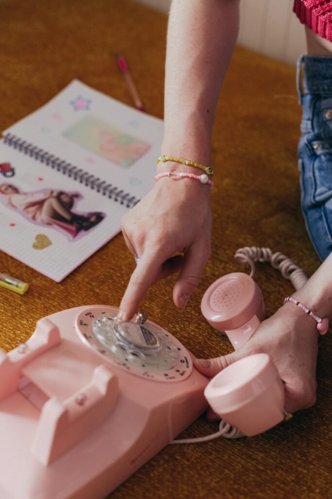 Retro-themed image featuring a pink rotary phone being dialed, evoking 90s nostalgia.